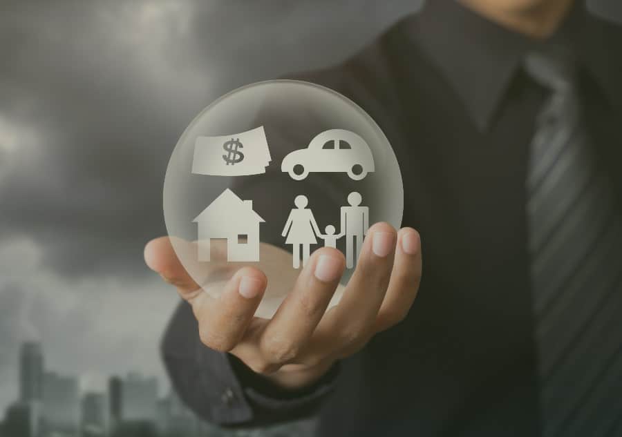 homem segurando uma bolha com ícones de dinheiro, casa, carro e família, indicando o que é seguro prestamista 