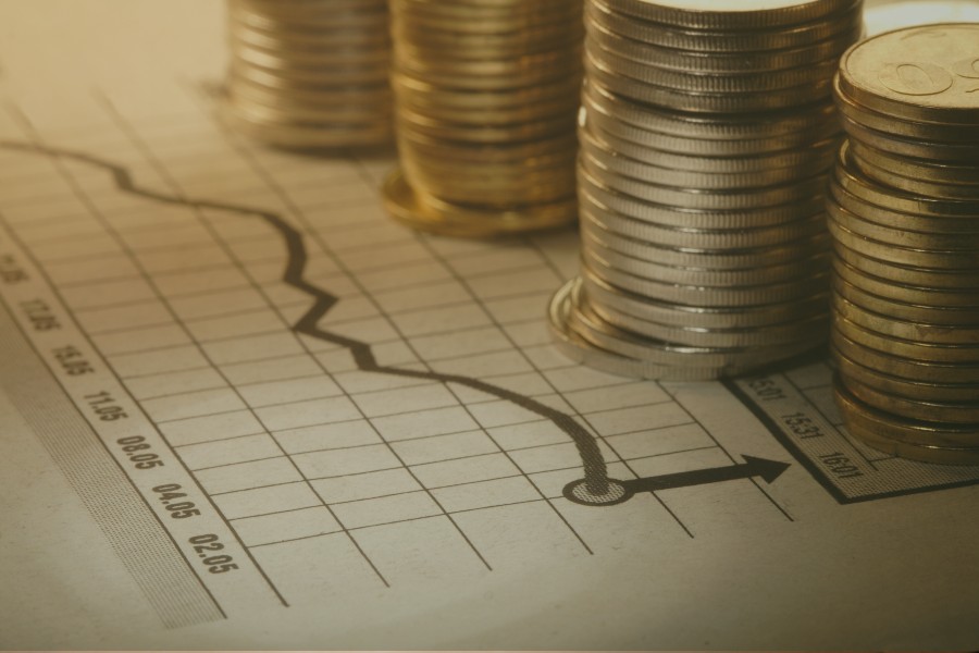 moedas empilhadas sobre um gráfico crescente, indicando o sucesso desse perfil de investidor