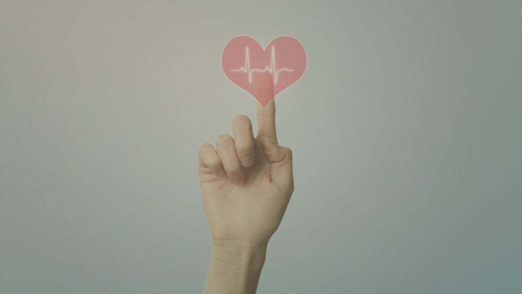 pessoa tocando um símbolo de coração com o indicador, representando o seguro de vida empresarial